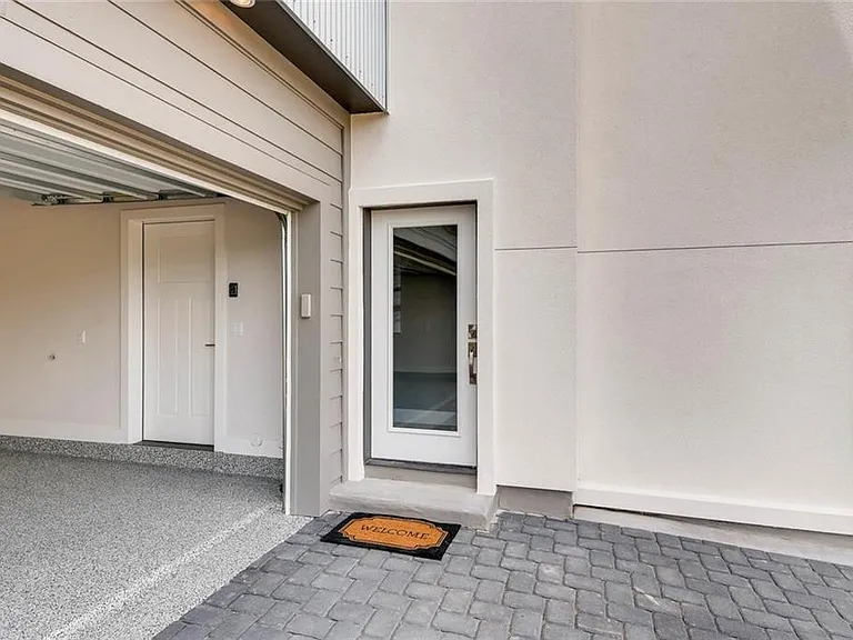 Garage entrance with a paver driveway, leading to a finished two-car garage and one of the private entrances to the condo.