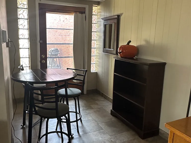 Interior table and chairs, next to the east door exit where table, chairs and grill are there for your enjoyment. Shelves have some games and puzzles.