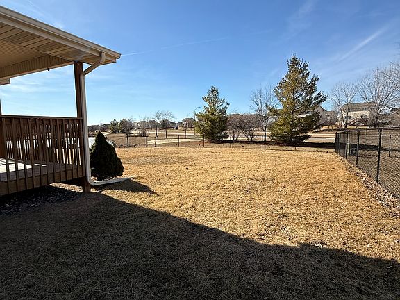 Rear fenced in yard. View of mature trees
