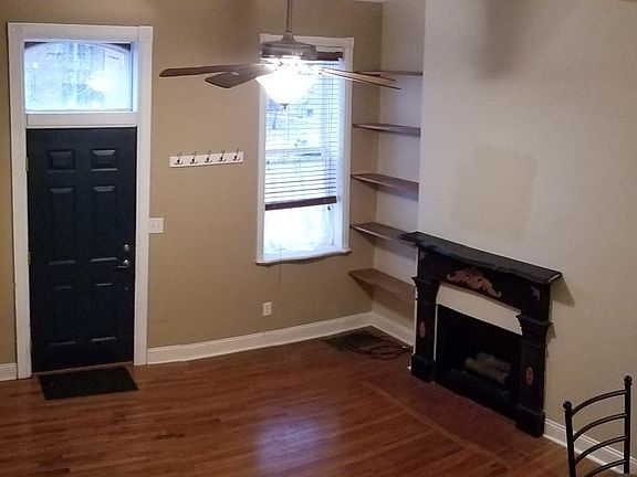 View from staircase. Functional fireplace, ceiling fan, hardwood floors, and high ceilings!