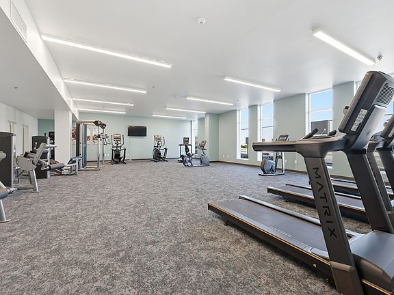 A modern, well-equipped fitness center designed for convenience and versatility, featuring a mix of cardio machines, strength-training equipment, and open space for stretching or functional workouts_all in a clean, inviting environment.