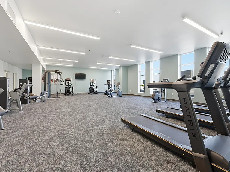 A modern, well-equipped fitness center designed for convenience and versatility, featuring a mix of cardio machines, strength-training equipment, and open space for stretching or functional workouts_all in a clean, inviting environment.