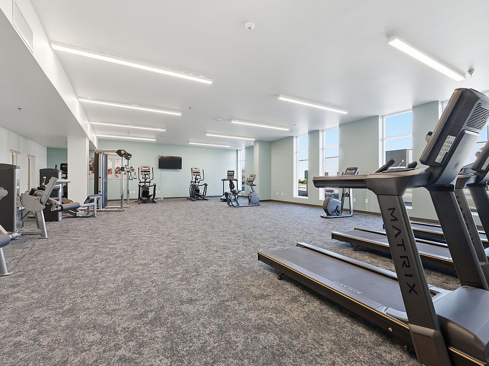 A modern, well-equipped fitness center designed for convenience and versatility, featuring a mix of cardio machines, strength-training equipment, and open space for stretching or functional workouts_all in a clean, inviting environment.