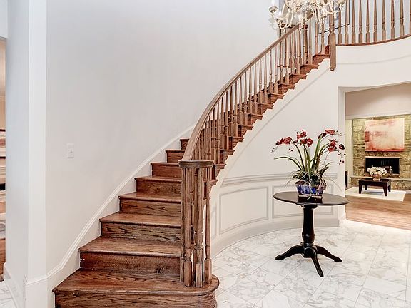 Gorgeous foyer with curved walls and staircase, marble flooring