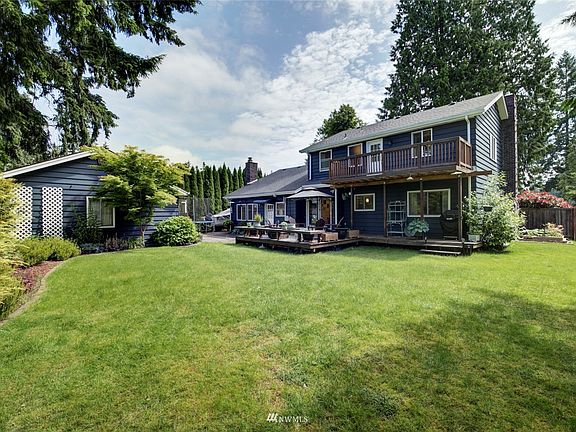 The spacious back yard is bordered by mature plants and trees. 