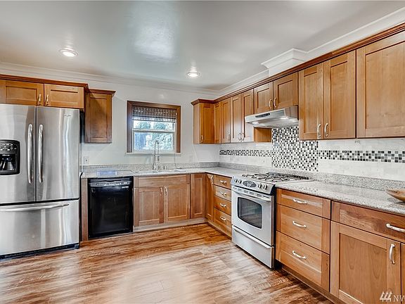 Gorgeous updated kitchen include granite countertops, full-height tiled backsplash, cherry cabinetry with crown molding, stainless refrigerator & stove gas range and new luxury vinyl plank flooring.