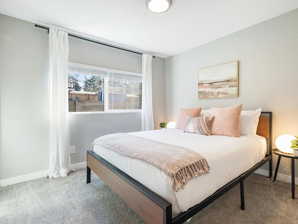 Bedroom features a large window with curtain panels, soft carpet, and space for a full/queen bed with nightstands.