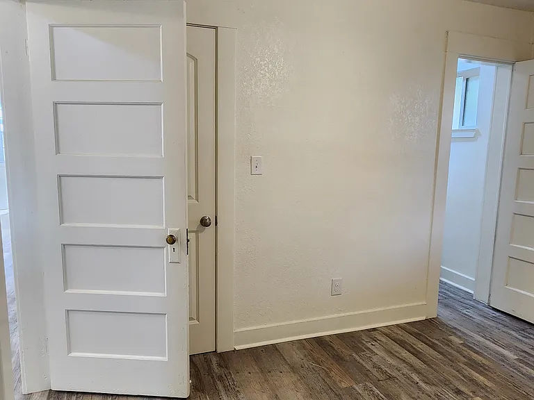 Back bedroom - door to kitchen area on left, closet door and door to bathroom on right.