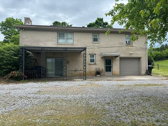 Back view of house with large driveway and one car garage