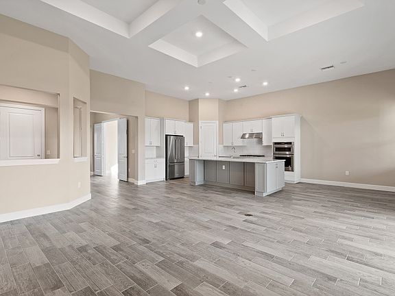 Spacious gathering room in an open floor plan with decorative coffered ceiling connecting tile flo