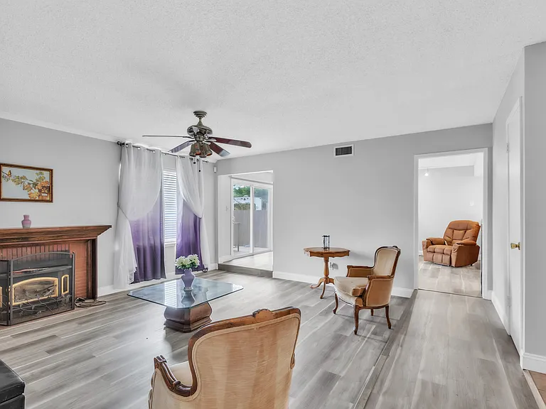 Sitting area facing the pool. Wooden floors with a ceiling fan.
