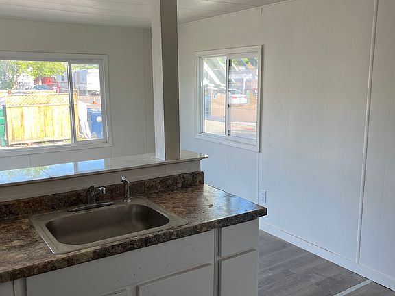 Kitchen to living. Sink, counter, cabinets.