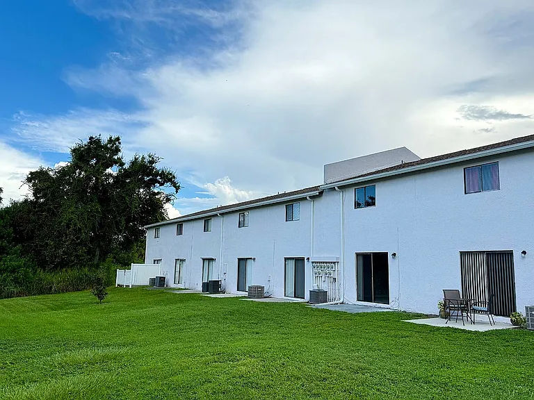 Beautiful townhouse row with vibrant green lawn and serene sky backdrop, ideal for modern suburban living.