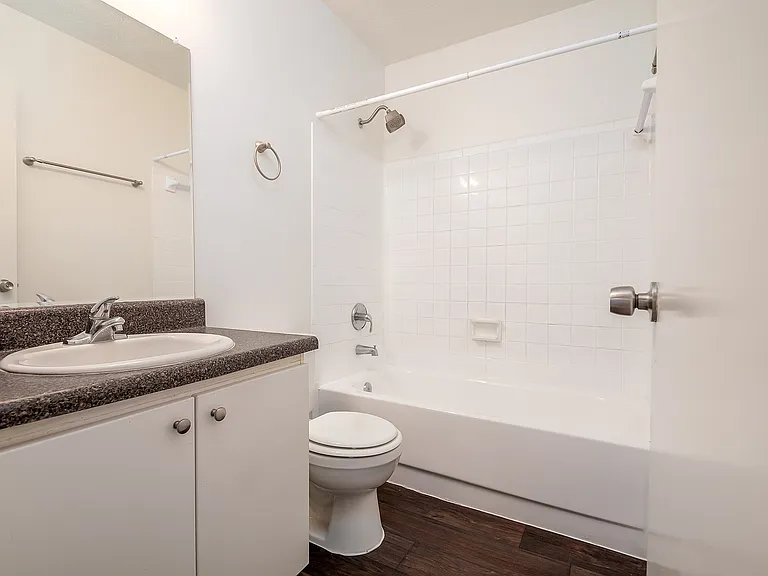 Modern bathroom with sleek white tiles, elegant vanity, and a clean bathtub, perfect for relaxation and rejuvenation.
