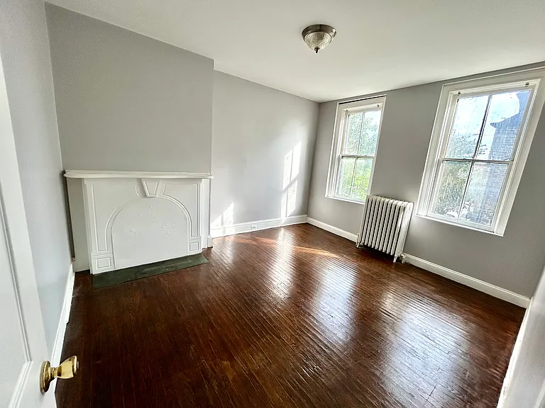 Beautiful bright bedroom with large windows and historic fireplace facade and mantle.