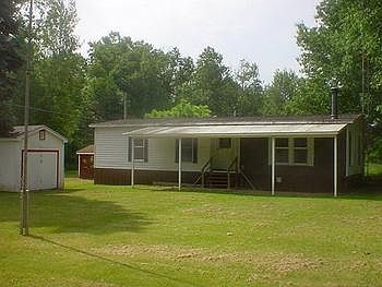 Side view of home with covered sitting area and the 2 sheds.