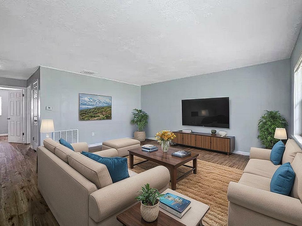 Inviting living room with cozy seating, modern decor, large flat-screen TV, and abundant natural light from expansive windows.
