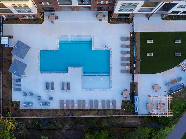 Aerial View of Resort-Style Pool, Lounge Areas, and Outdoor Gaming Lawn