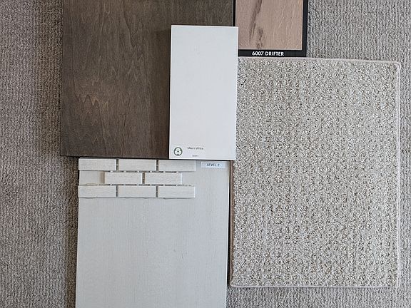A collection of Voyager 220 floor and tile samples in neutral tones arranged on a carpeted surface.
