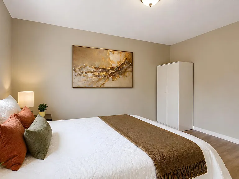 Spacious bedroom with a large window for natural light, a comfortable bed setup, and a freestanding wardrobe for storage.
