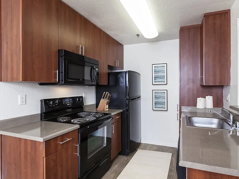Classic Package kitchen with black appliances, dark grey laminate countertops, cherry cabinetry, and hard surface flooring