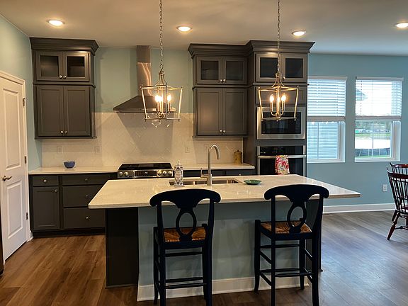 Kitchen island with quartz countertop, pantry door is in the left rear of photo