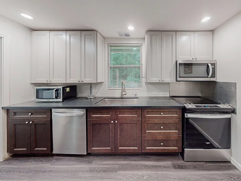 Efficient kitchen with ample cabinetry, generous counter space, stainless appliances, and a window over the sink.