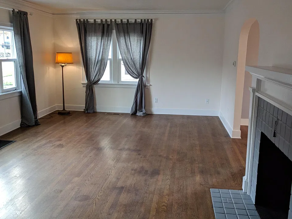The living room is large with a vintage fireplace and lots of natural light.