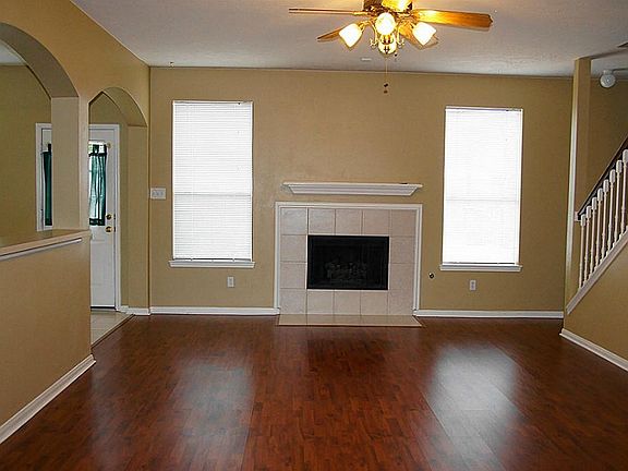 Family room with laminate wood floors, fireplace with gas logs, double windows, high ceiling and decorative fan.