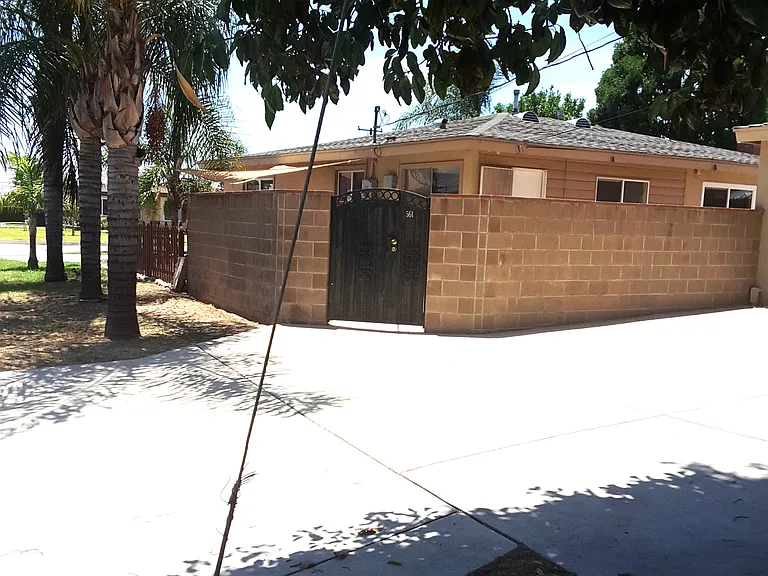 Entrance to the back yards, from the driveway featuring a nice newer high block wall and a lockable iron door. Both sides of the streets have nice palm trees.