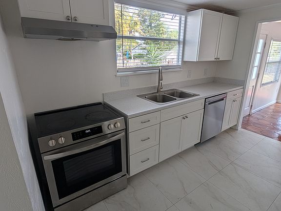 Kitchen Left side. More cabinets and Fridge on right side.