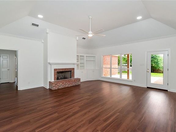 Unfurnished living room with visible vents, ceiling fan, and vaulted ceiling