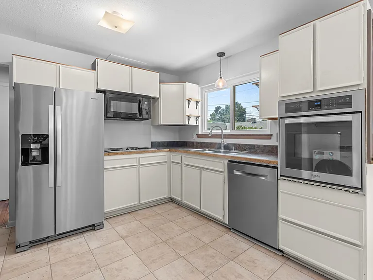 Neutral painted cabinetry and newer stainless steel appliances, including a French-door refrigerator.