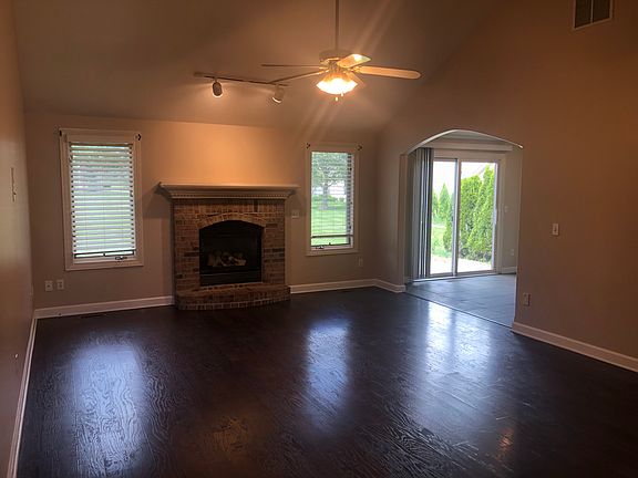 Living room with accent lighting over self-starting fireplace. New ceiling fan / light fixture. Archway to dining area and kitchen