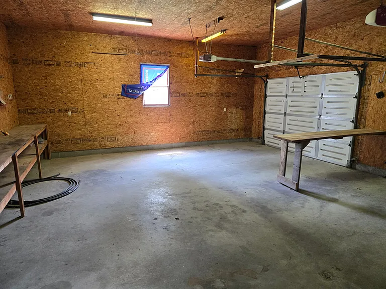 Huge insulated and heated garage with floored attic access and work tables.
