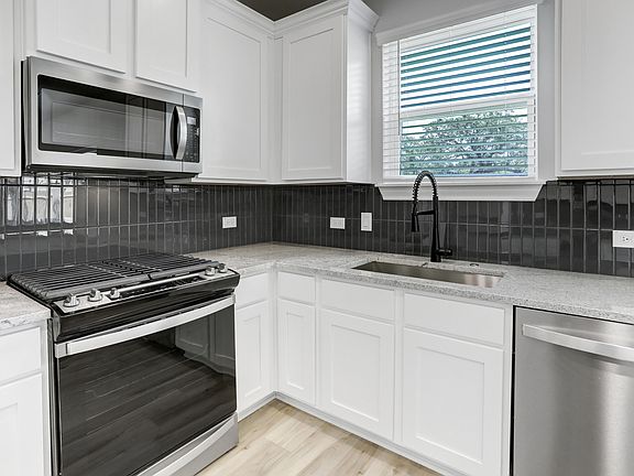 Gorgeous kitchen with tile backsplash, granite countertops, and faux wood blinds.