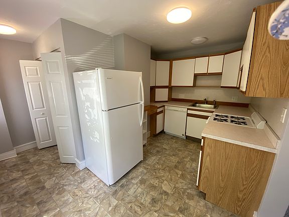 Kitchen with gas range, dishwasher and refrigerator.
