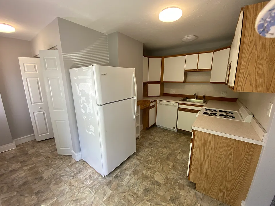Kitchen with gas range, dishwasher and refrigerator.