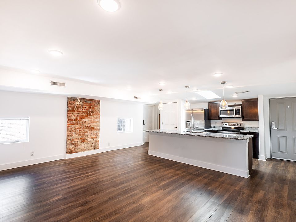 Un-staged photo shows off the luxury vinyl plank floors, large island, and exposed brick.