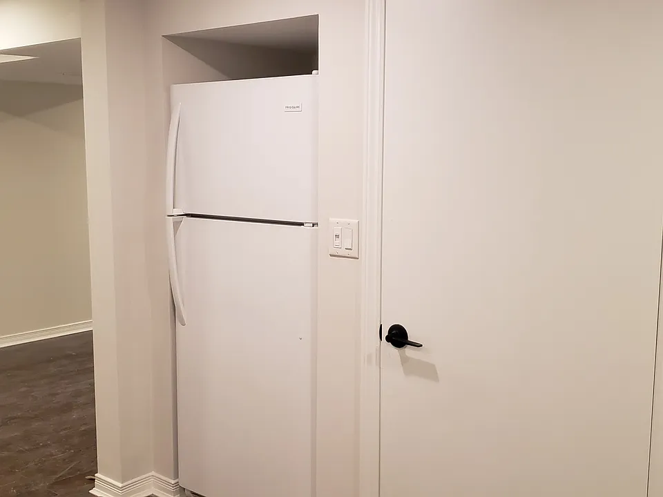 Part of the kitchen showing the fridge. The door to the right enters into a large laundry room.
