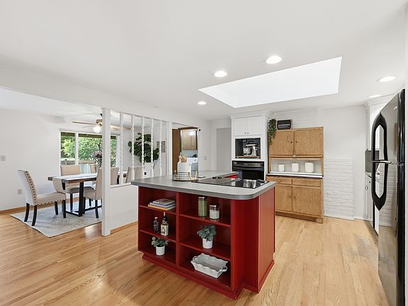 Open-concept kitchen with skylight, breakfast bar, and dining area beyond