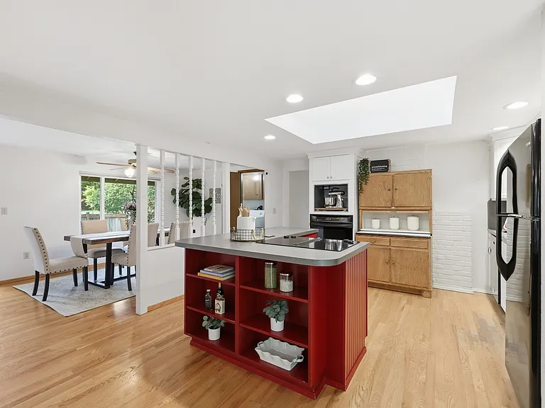 Open-concept kitchen with skylight, breakfast bar, and dining area beyond