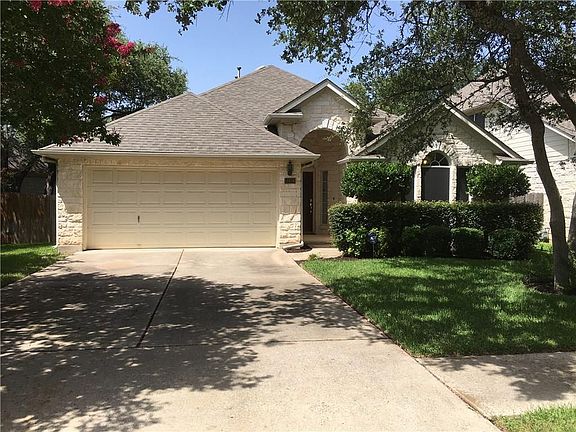 Single story white limestone home in gated community.