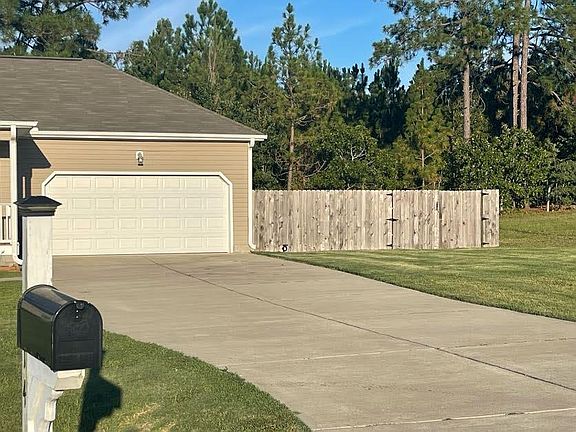 Vast driveway, also showcasing fenced in backyard.