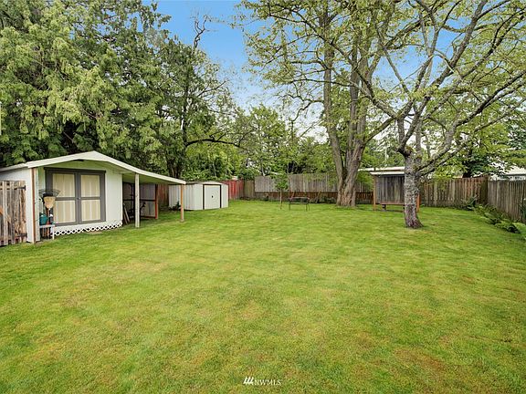 The fully fenced oversized lot is highlighted by mature trees, functional outbuildings & a partially covered patio perfect for soaking in the summer weather!
