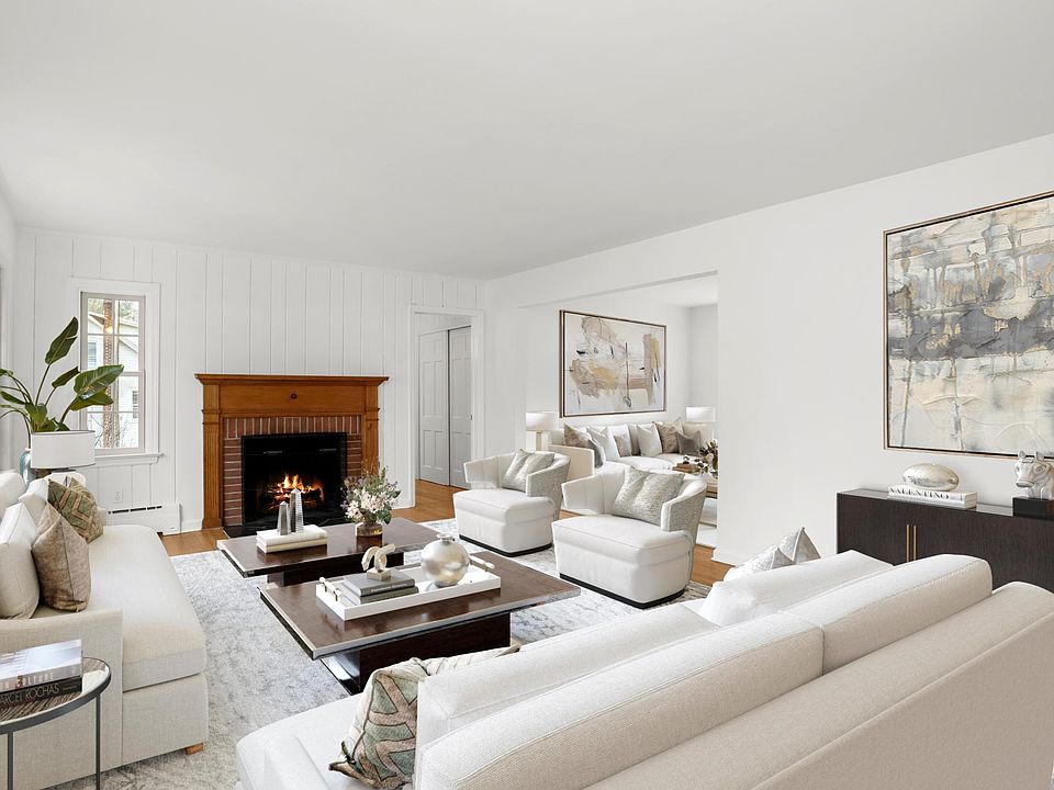 virtually staged living room with adjacent family room. Door to right of fireplace leads to primary bedroom