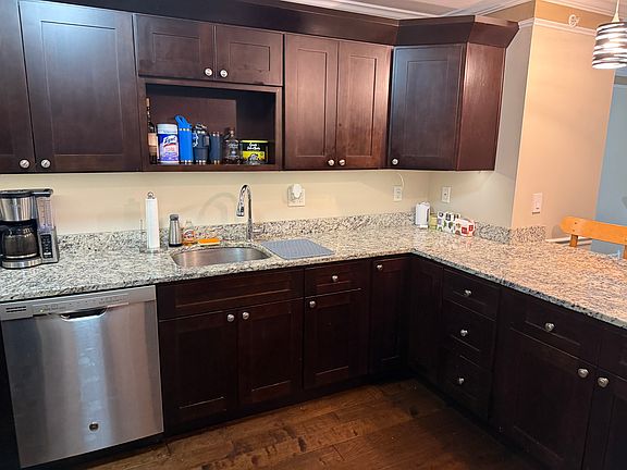Kitchen with double ovens, modern appliances, hardwood cabinets, and hanging light fixtures