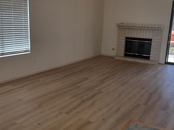 Viewed from front door. Living area, new in 2024, plank vinyl living room and portion of rear covered concrete patio. Concrete patio runs to the right all along the house past the master bedroom.