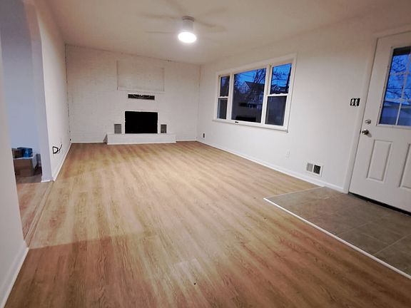 Large living room with wood burning fireplace and water views out the door and windows.