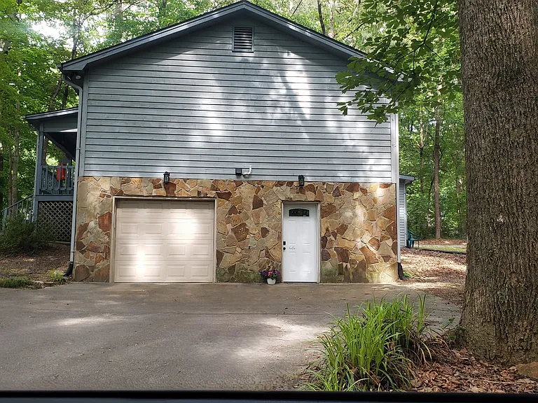 The exterior of the home showing the parking area, single garage, and private entry for the apartment.